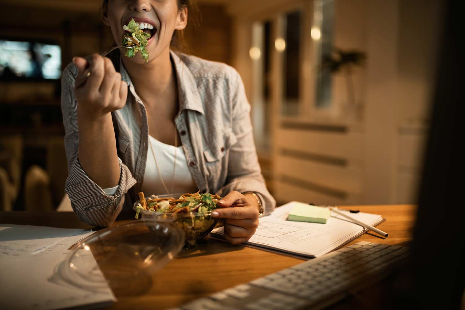 female-freelancer-using-computer-eating-salad-night-home.jpg